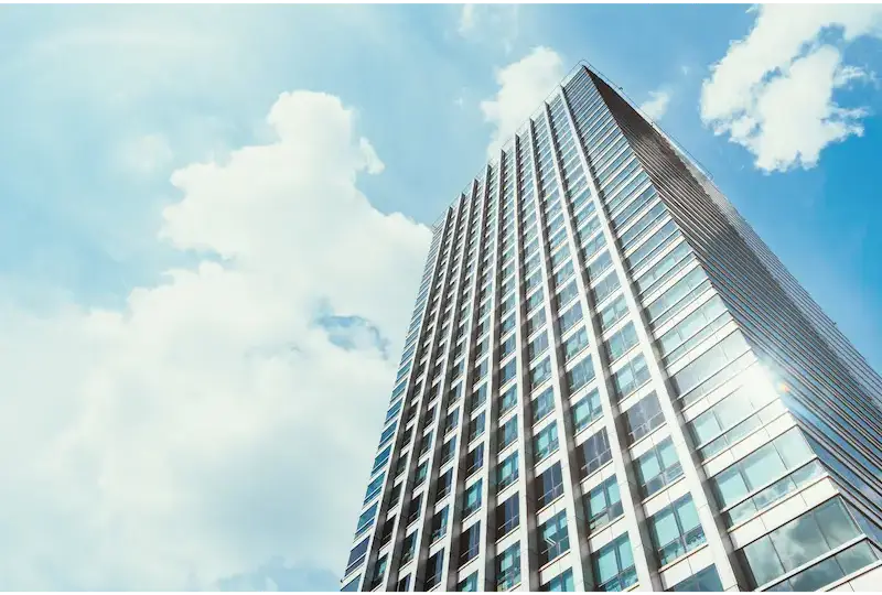 A tall modern skyscraper against a blue sky with clouds.