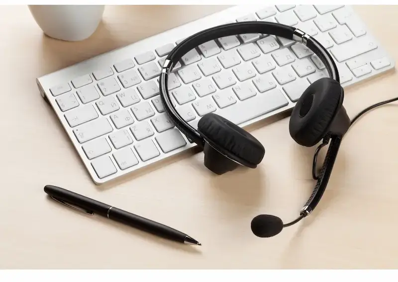 A white keyboard and a black headset on a desk